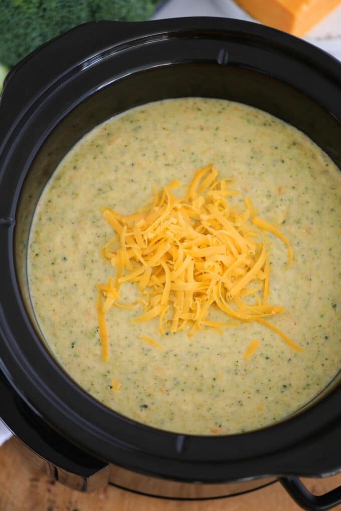 Broccoli cheddar soup topped with shredded cheddar cheese in the crockpot.