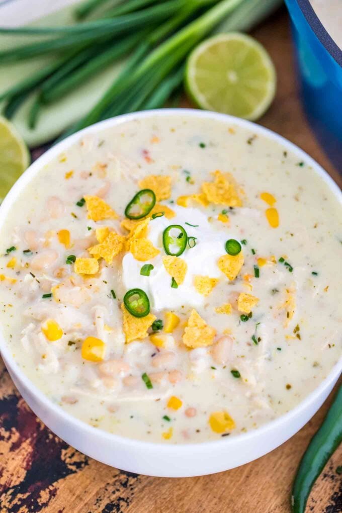 Easy white chicken chili in a white bowl garnished with chips, and sour cream