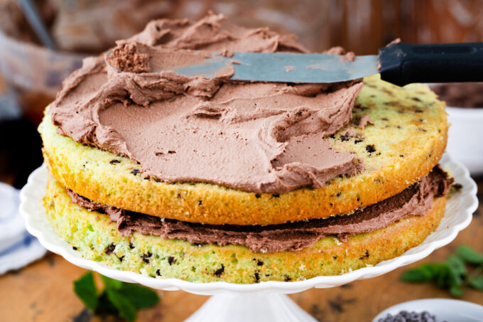 Frosting mint chocolate chip cake layers.