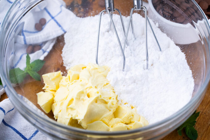 Beating butter and powdered sugar.
