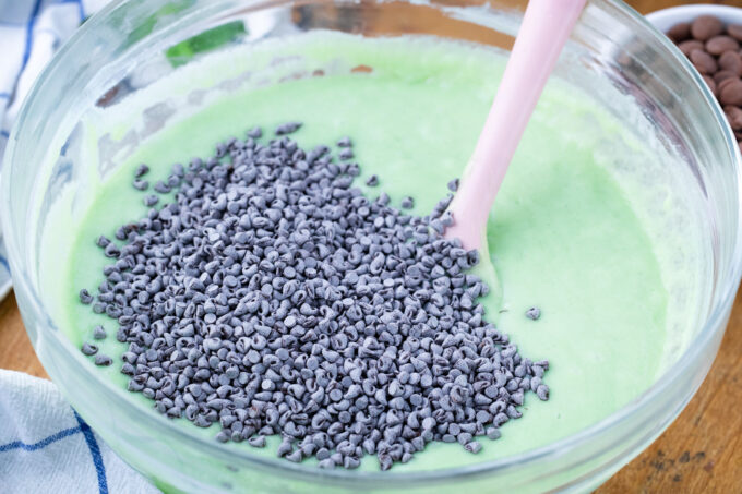 Stirring mini chocolate chips into mint cake batter.