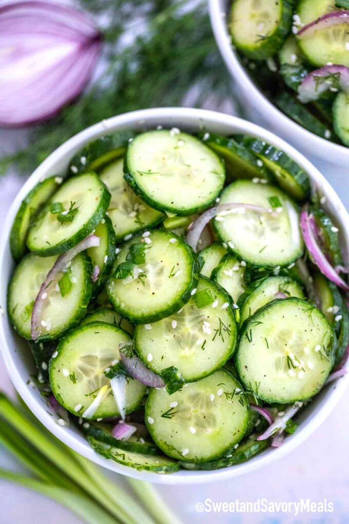 freshly sliced cucumber salad with red onion, dill, and sesame seed in a bowl.