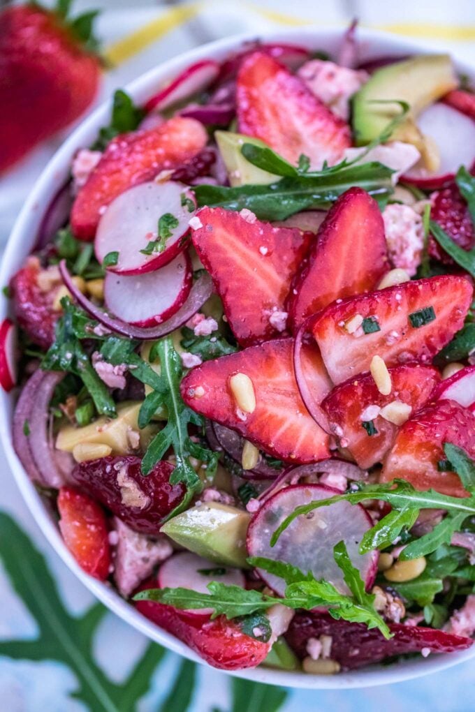 Homemade arugula strawberry salad in a white bowl