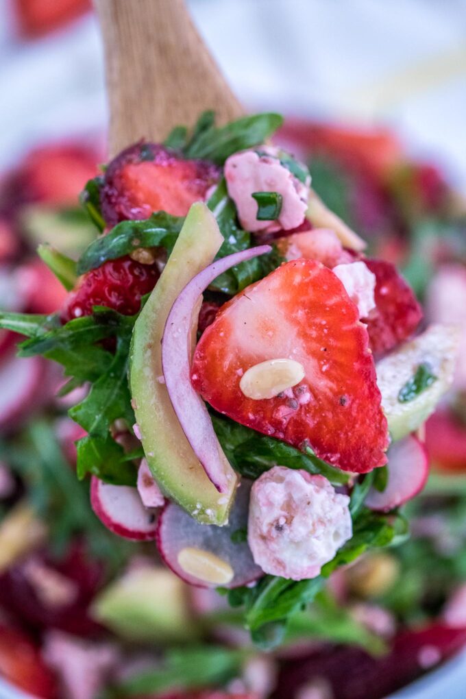 A spoonful of arugula strawberry and avocado salad