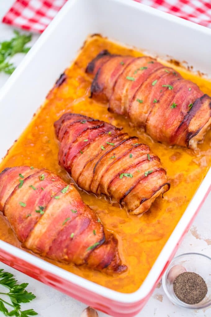 cooked bacon wrapped chicken breasts in a baking dish