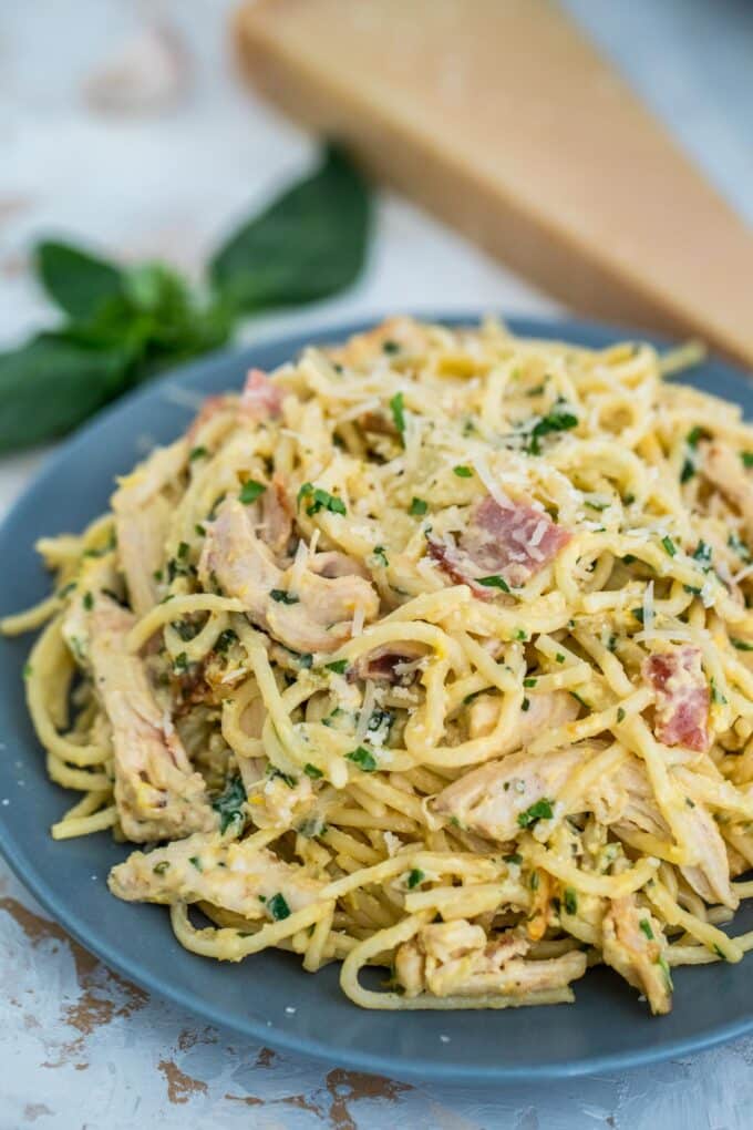 Chicken carbonara and bacon pasta topped with shredded Parmesan cheese on a plate
