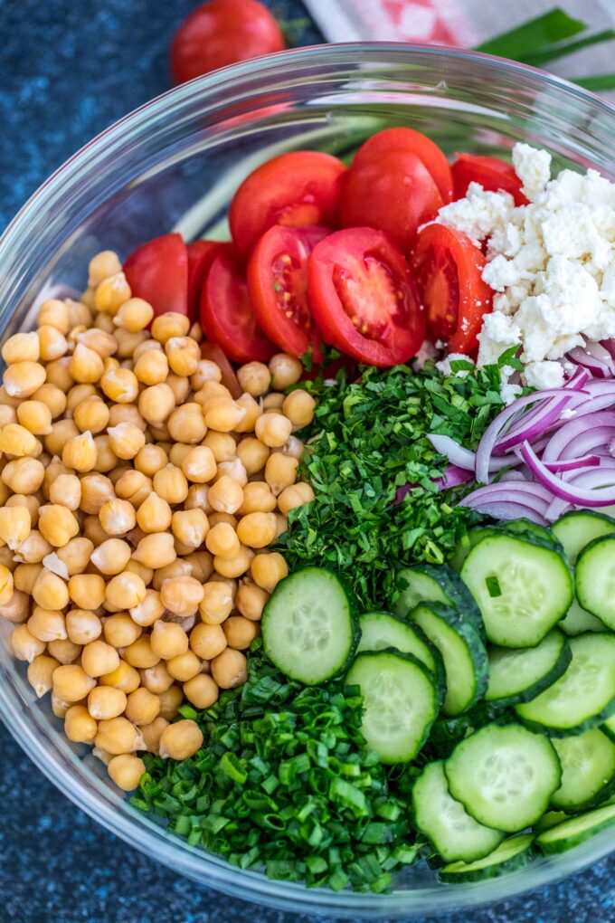 Chickpea salad ingredients in a large glass bowl.