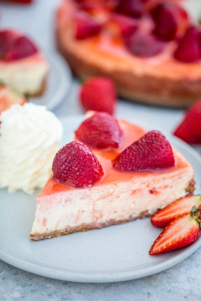 Strawberry Cheesecake Slice topped with strawberries and whipped cream on the side