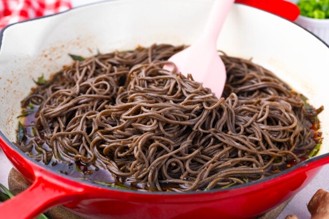 Tossing soba noodles in a soy sauce based sauce.