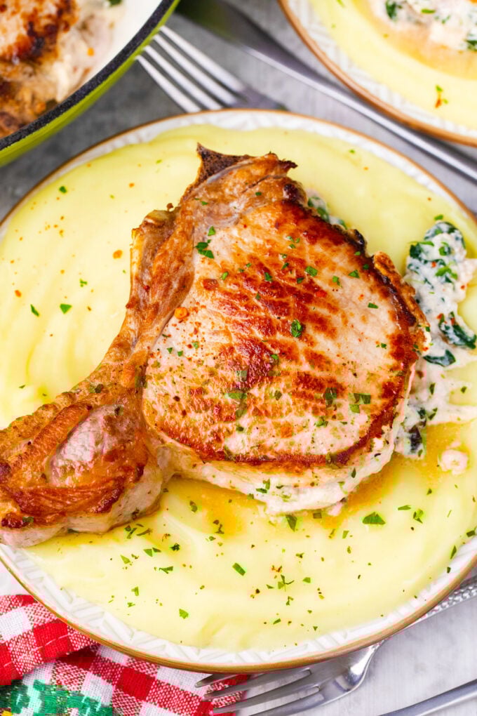 Homemade cheesy spinach dip stuffed pork chops over mashed potatoes.