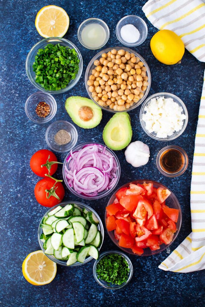 Overhead shot of chickpea salad ingredients in bowls on a table.