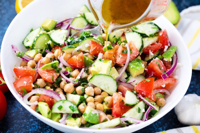 Pouring dressing over chickpea salad.