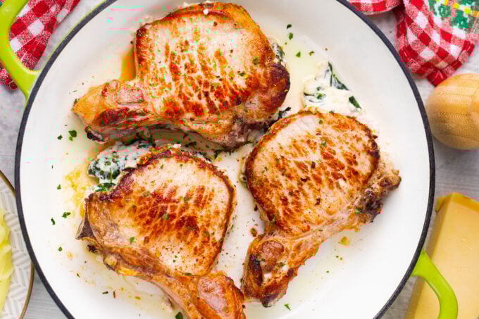 Overhead shot of cheesy spinach dip stuffed pork chops in a pan.