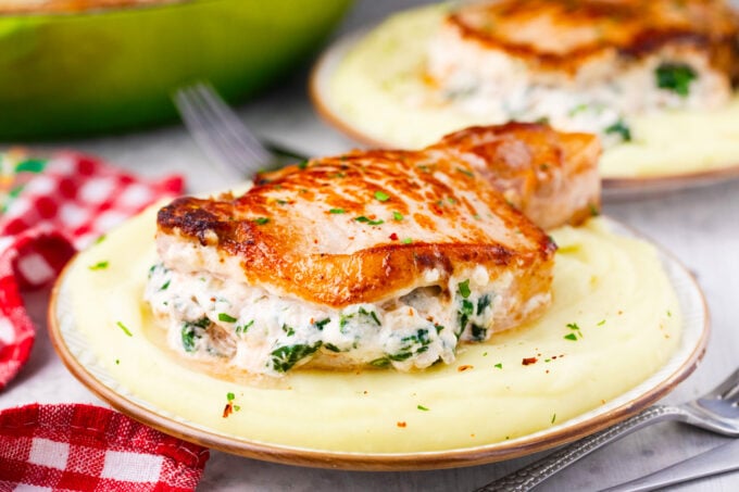 Cheesy spinach dip stuffed pork chops served with mashed potatoes.
