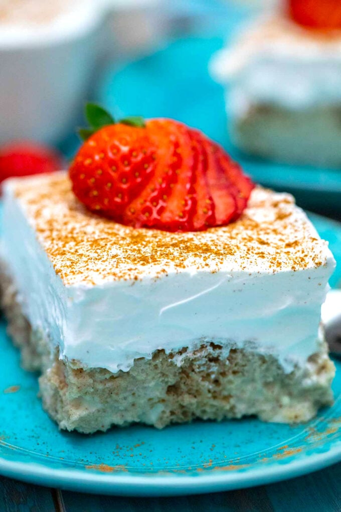 a slice of tres leches cake with whipped cream cinnamon and strawberries