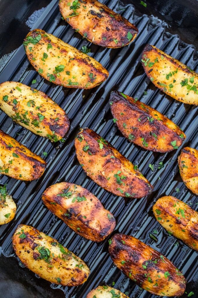 Sliced and seasoned potatoes on a grill.