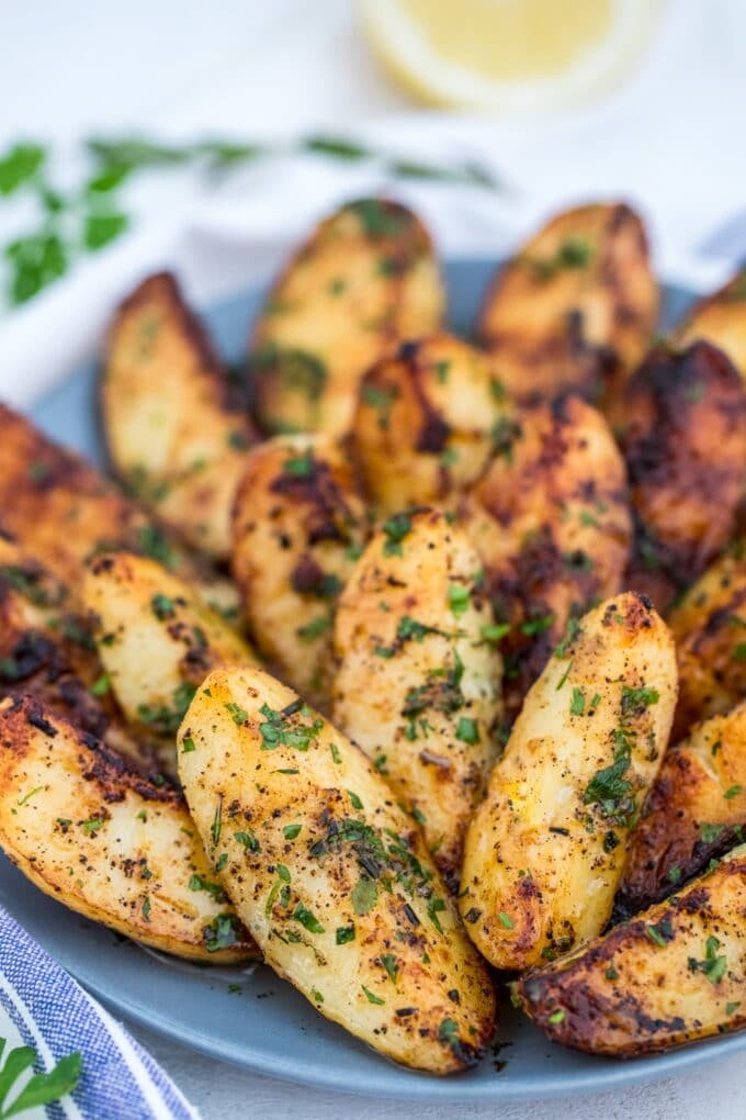 Grilled potato wedges garnished with chopped parsley on a plate. 