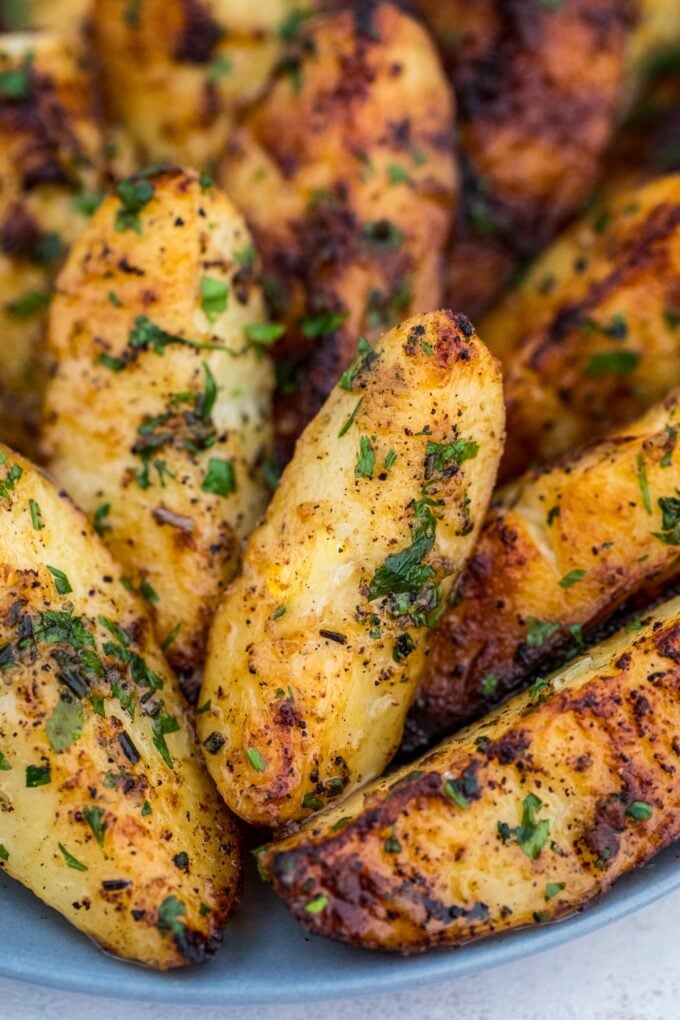 Grilled potatoes on a plate garnished with chopped parsley. 