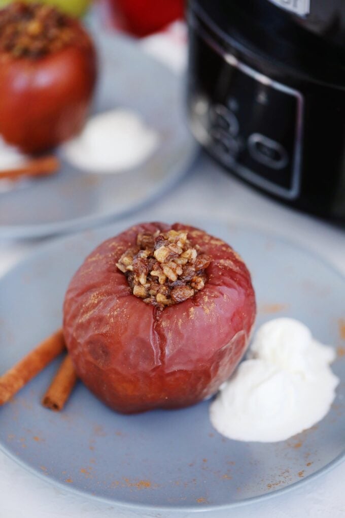 Baked apple stuffed with chopped walnuts and brown sugar on a plate with a scoop of ice cream on the side