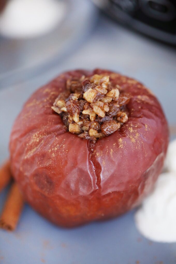 Stuffed baked apple with chopped walnuts with vanilla ice cream and cinnamon sticks on the side