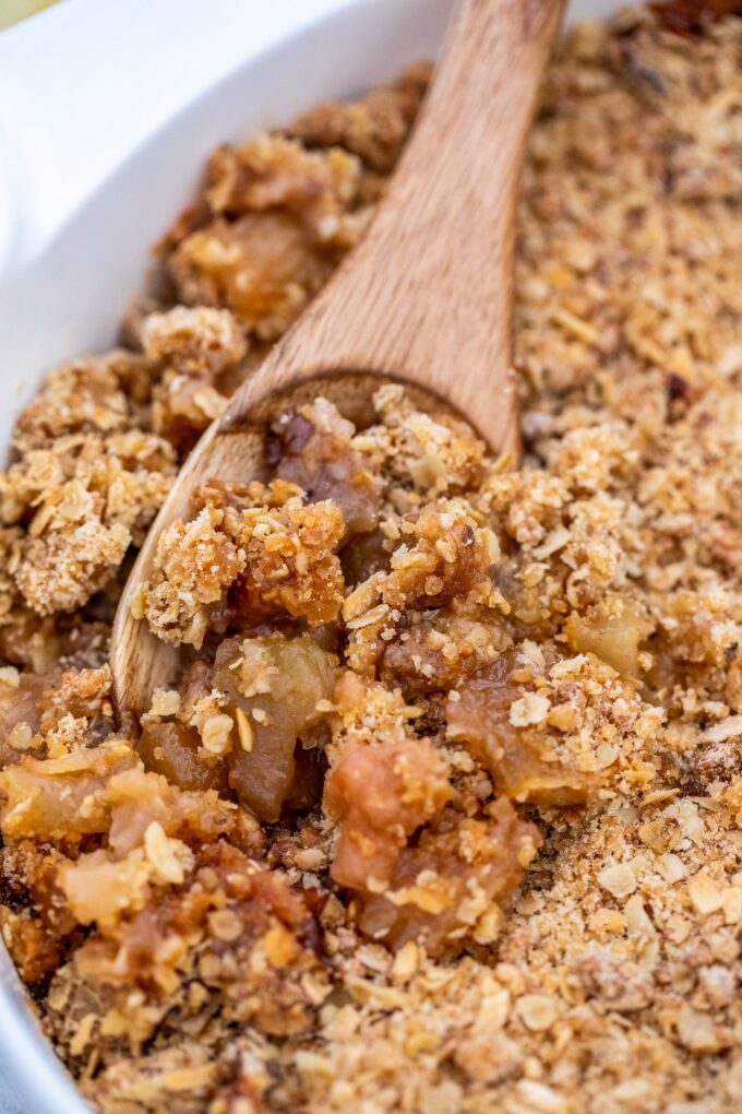 a wooden spoon scooping some homemade Apple Crumble from a baking dish