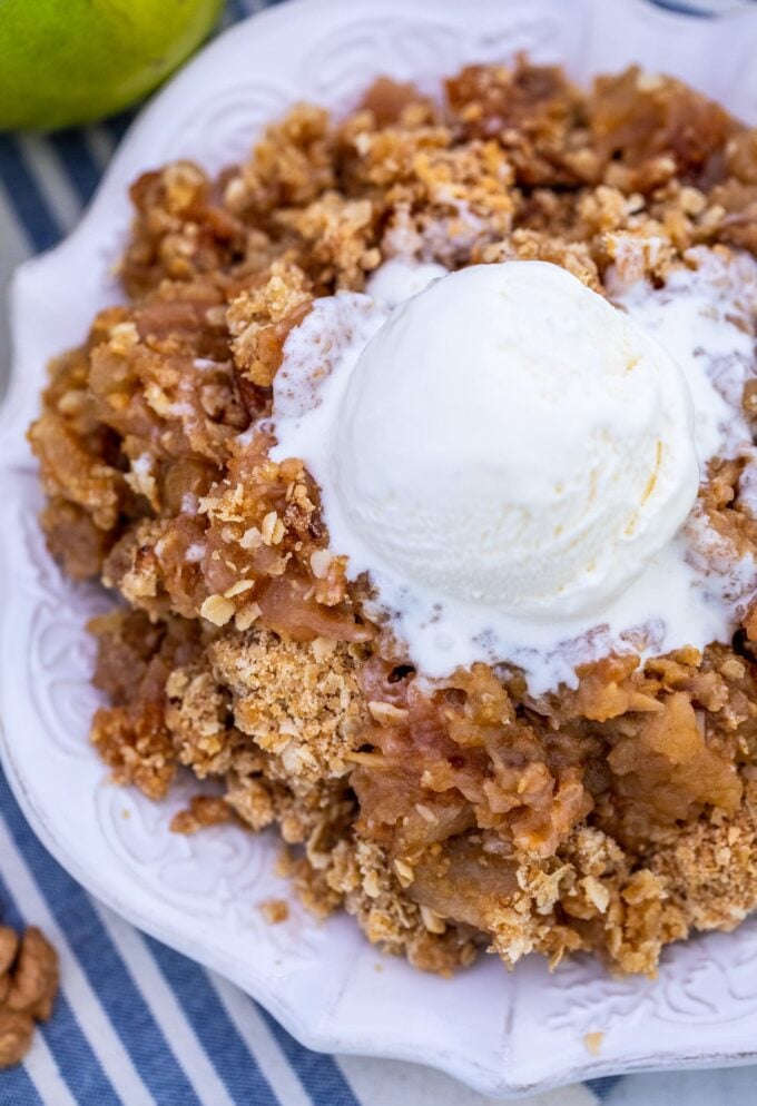 overhead shot of homemade apple crumble on a serving plate, topped with vanilla ice cream