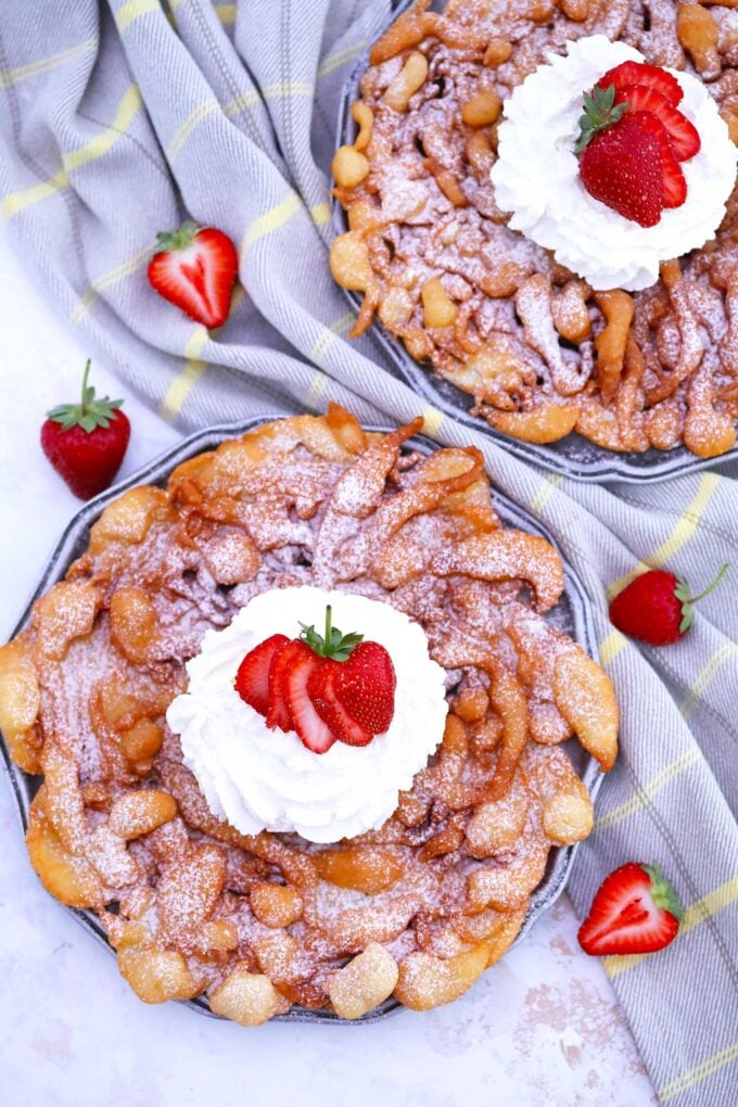 Picture of funnel cake topped with whipped cream and strawberries.