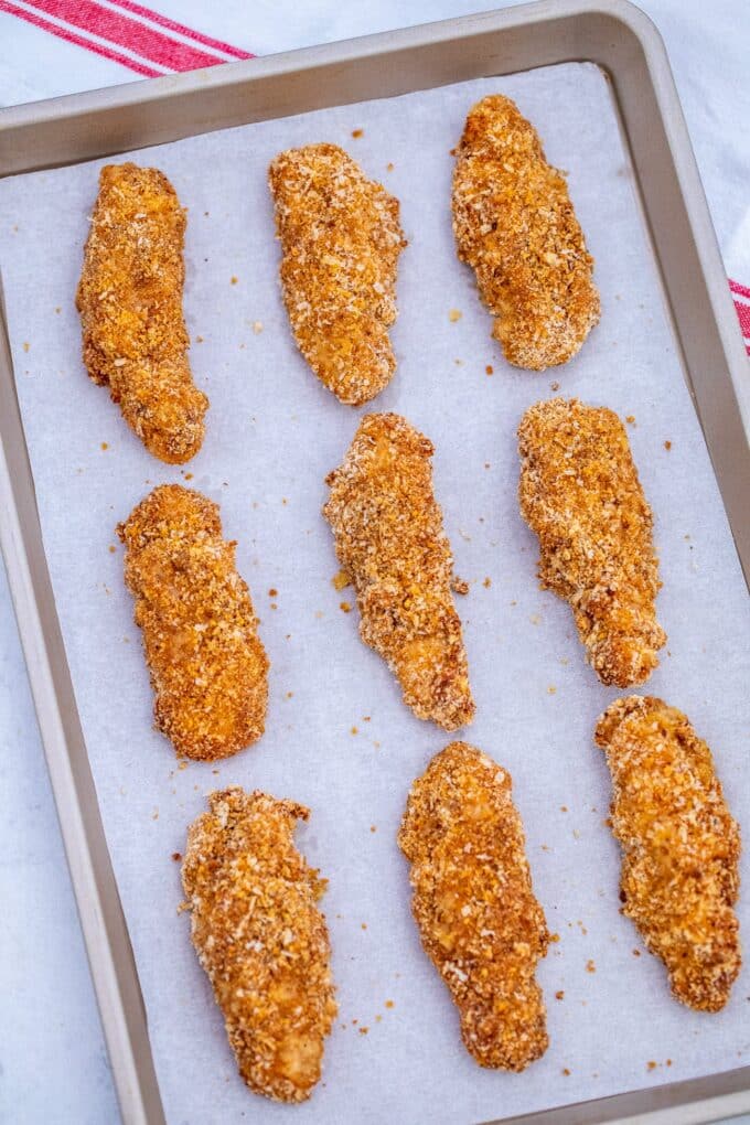 Breaded chicken tenders on a baking sheet.