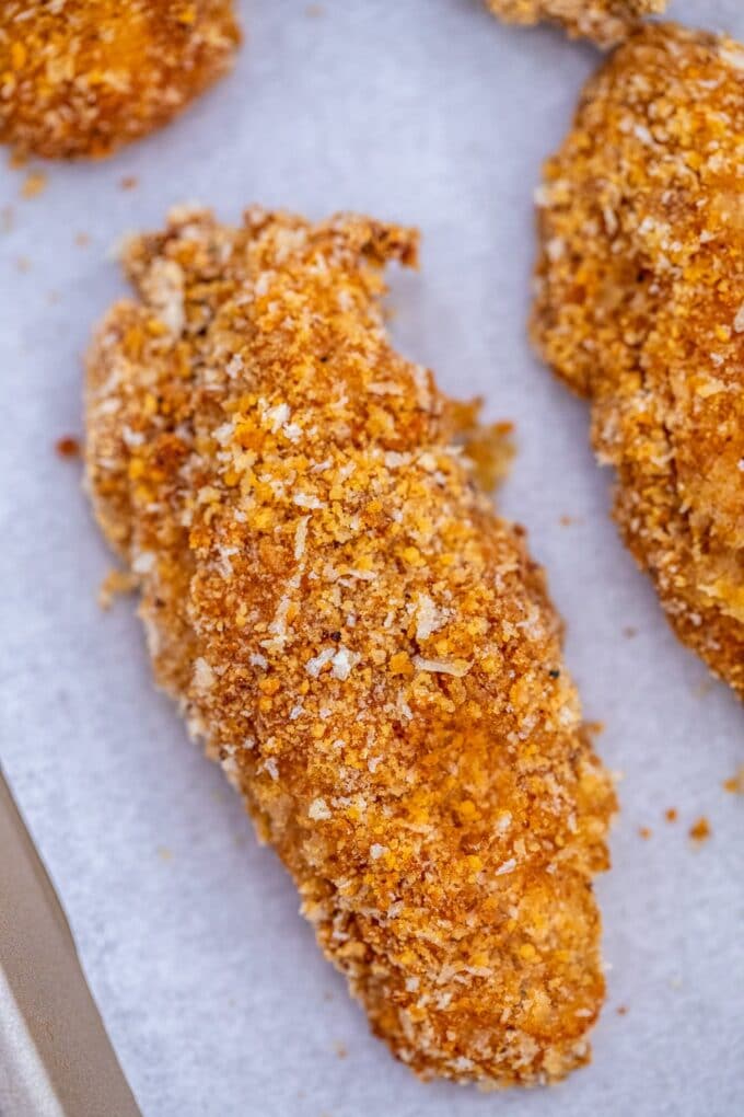 Breaded chicken tenders on a baking dish.