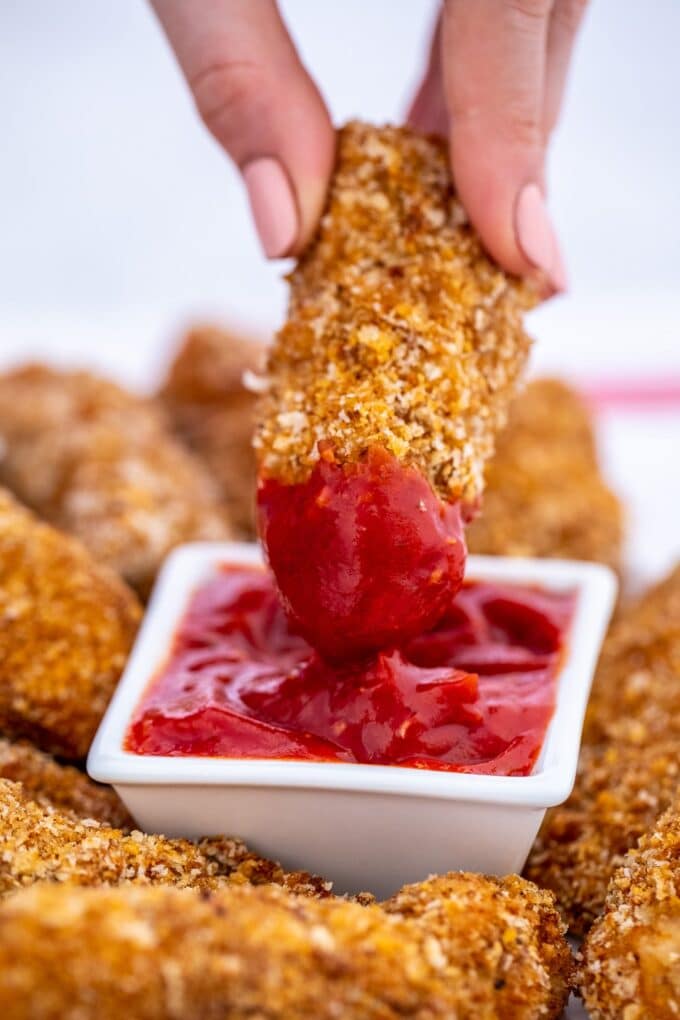 Crispy oven baked chicken tenders dipped in ketchup.