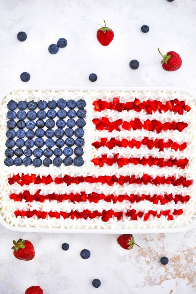 Patriotic Poke Cake with blueberries resembling the stars on the flag and strawberries for the red stripes