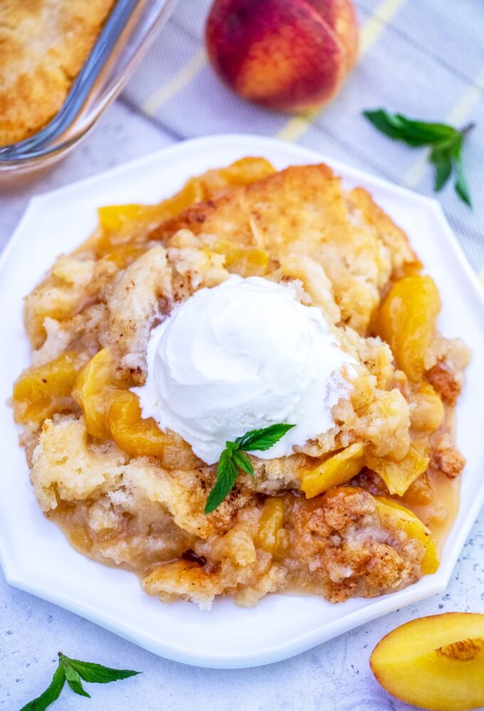 Image of peach cobbler topped with a scoop of ice cream. 