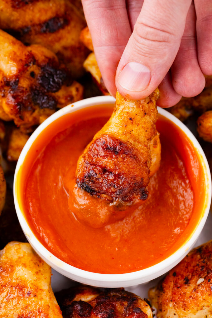 Dipping grilled chicken wing in Buffalo sauce.