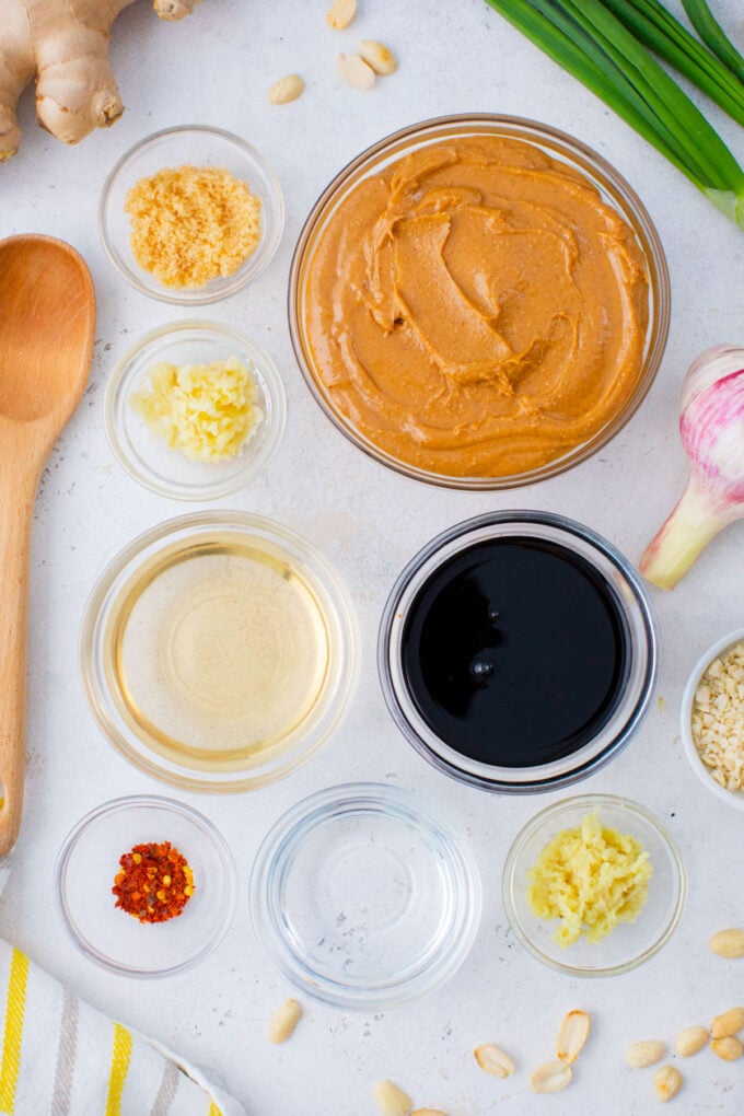 Overhead shot of Asian creamy peanut sauce ingredients in bowls on a table.