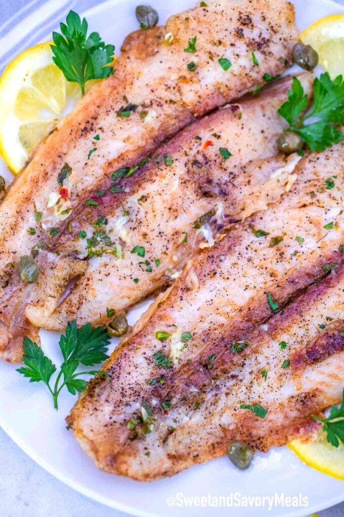 Swai fish fillets on a plate with lemon and parsley