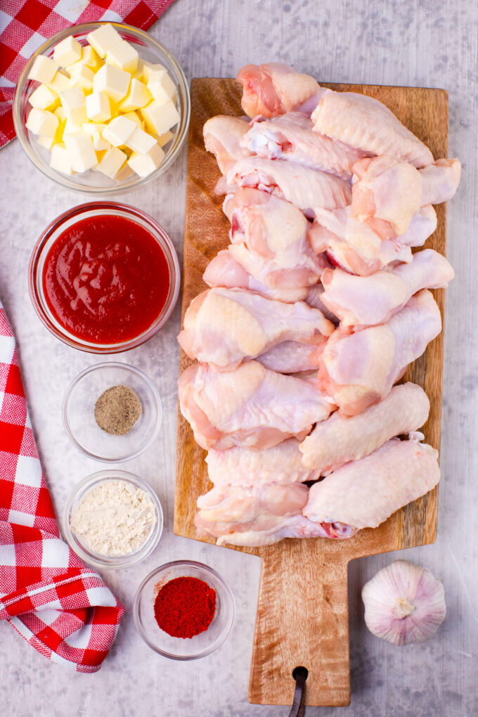 Overhead shot of grilled chicken wings ingredients arranged on a white surface.