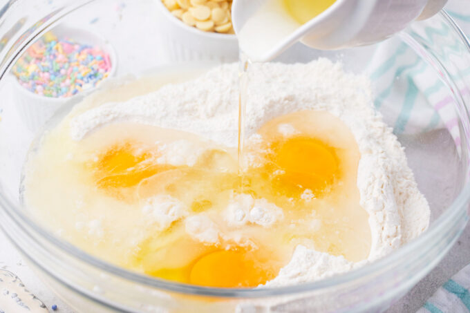 Mixing unicorn poke cake ingredients in a bowl.