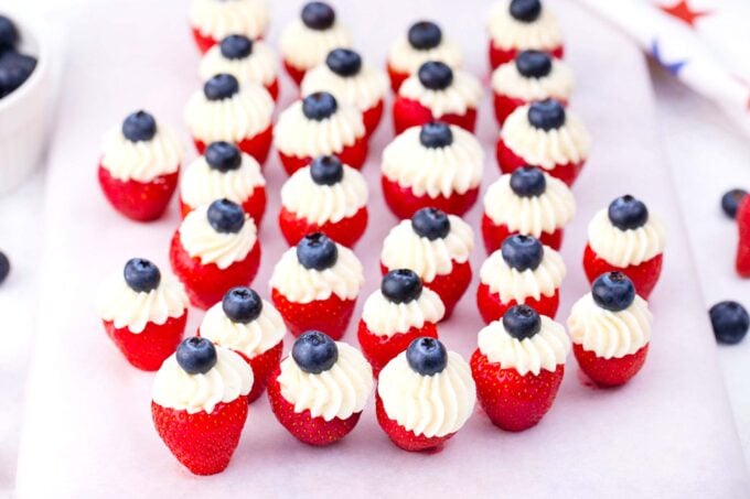 Red, white, and blue cheesecake stuffed strawberries with blueberries.