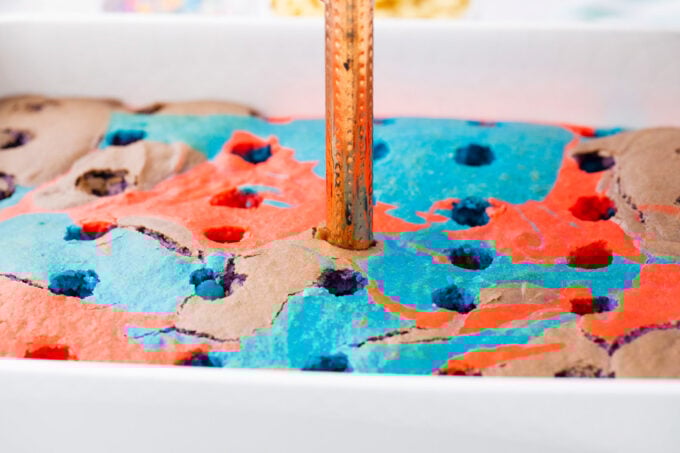 Making holes in unicorn sheet cake.