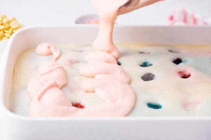 Spreading strawberry pudding over unicorn poke cake.