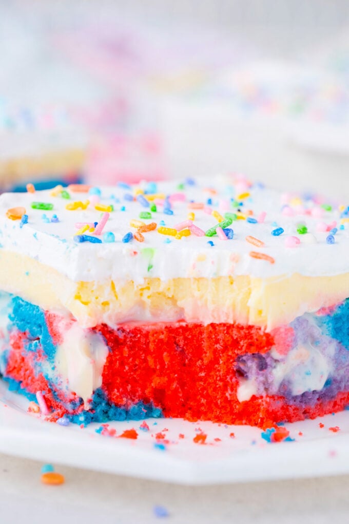 Unicorn poke cake with pudding and whipped cream.