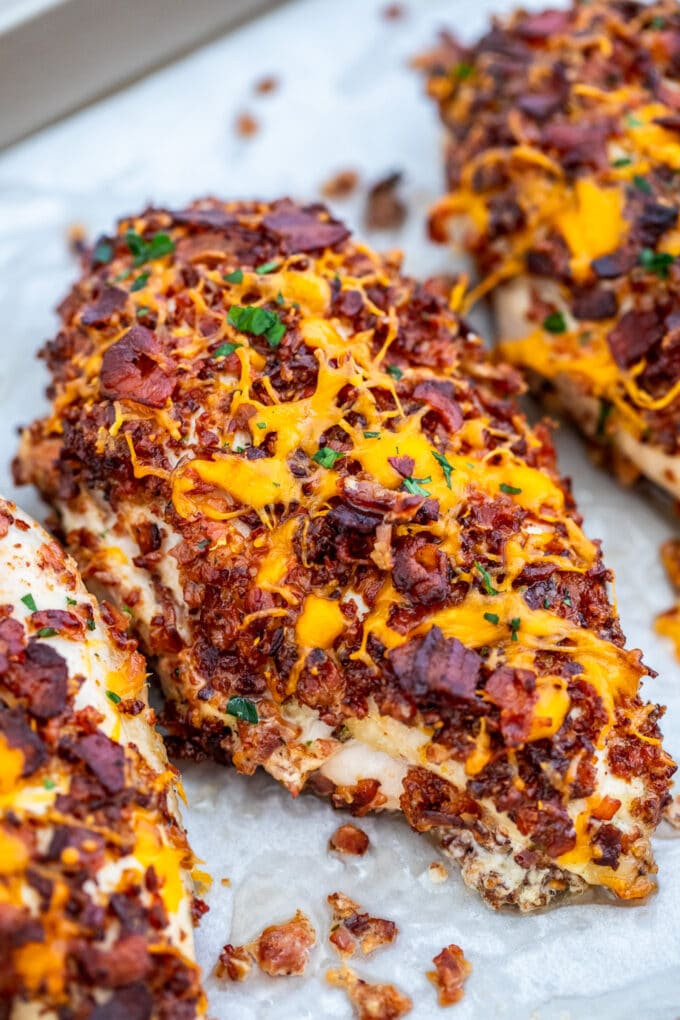 Image of baked chicken breasts stuffed with cheese and topped with bacon. 