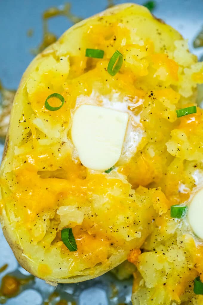 Microwave baked potato garnished with butter and chopped green onion.