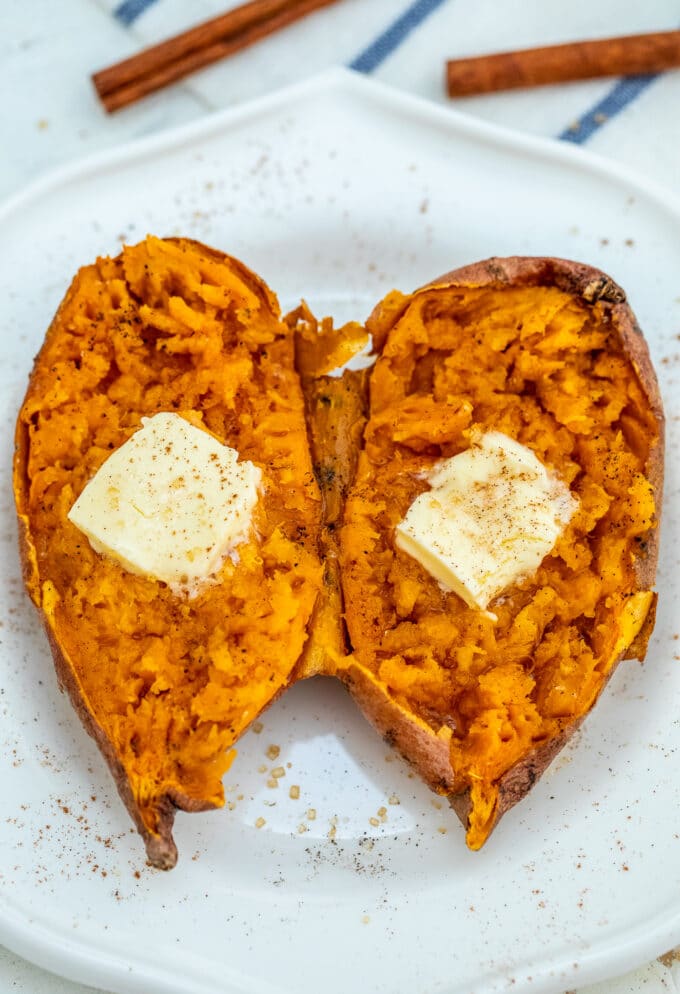 Sweet potato topped with butter and cinnamon on a white plate