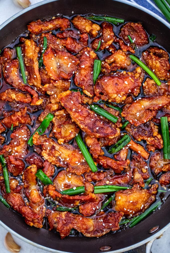 Crispy sliced chicken breast with green onion in a skillet