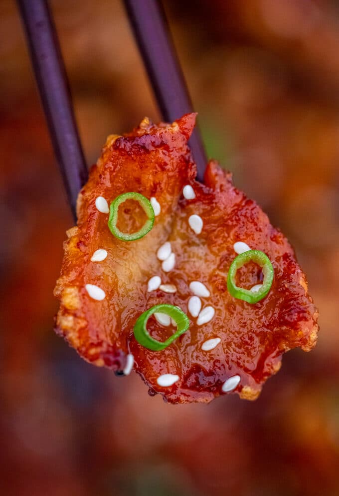 A slice of crispy chicken breast with Mongolian sauce, green onions, and sesame seeds