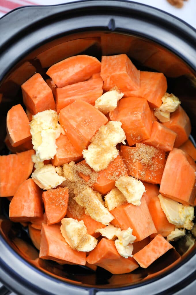 Sweet potatoes cut into cubes and topped with butter and cinnamon in the crockpot