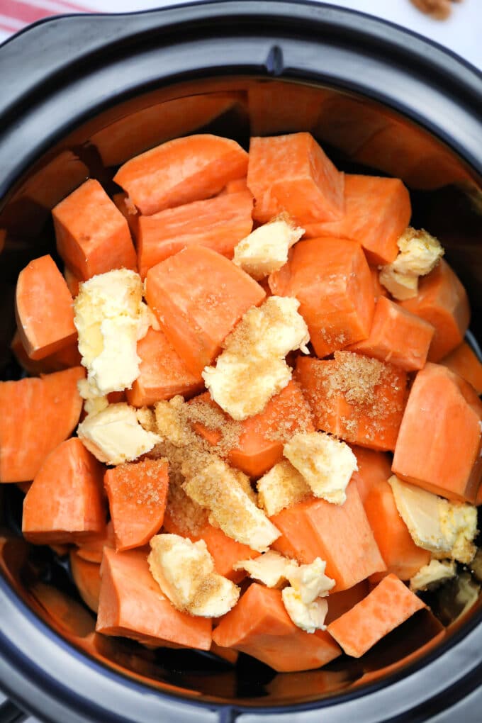 Sweet potatoes cut into cubes and topped with butter and cinnamon in the crockpot 