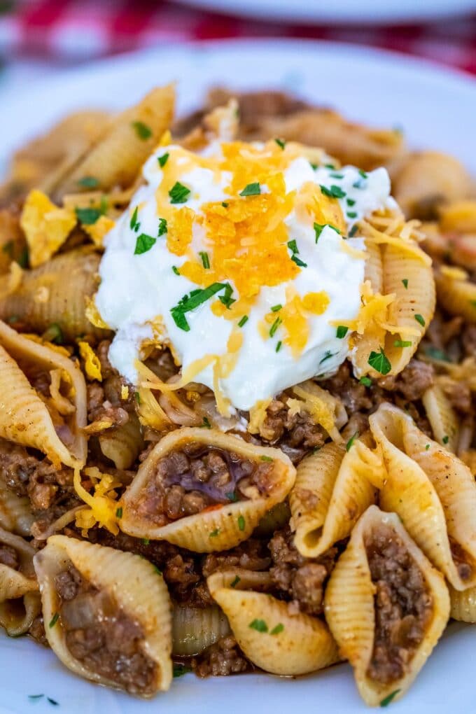 a plate of taco pasta garnished with sour cream and shredded cheese