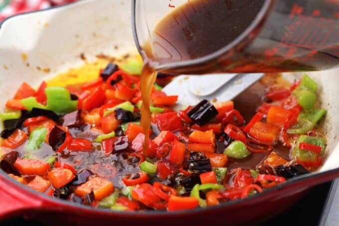 Adding Kung Pao sauce to stir fried veggie in a skillet.